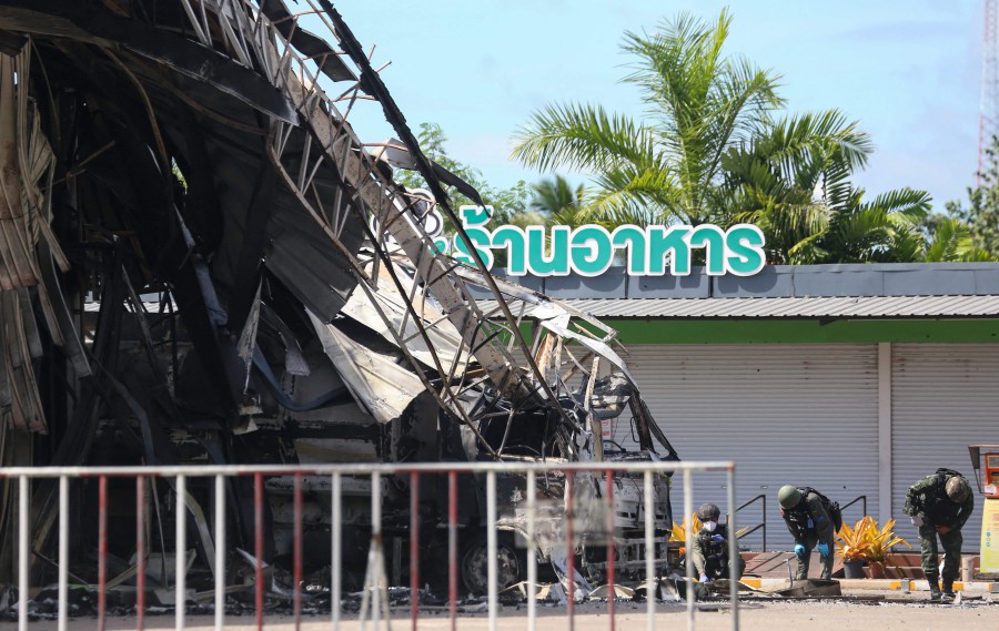 Thai bomb squad personnel inspect the damage at Bangchak gas station after an attack, in Nong Chik District in southern Thailand's Pattani province. - AFP PIC