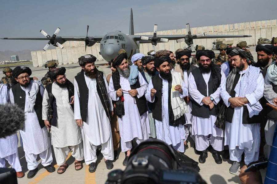Taliban spokesman Zabihullah Mujahid (C, with shawl) speaks to the media at the airport in Kabul. - AFP PIC