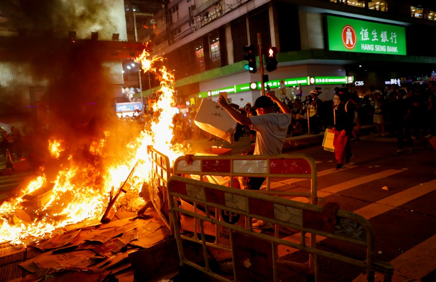 Protestor throws a box on a burning barricade during a demonstration in Mong Kok district in Hong Kong. - Reuters