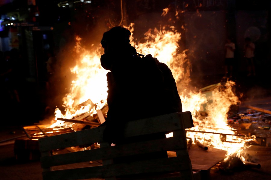 An anti-extradition bill protester walks near a burning barricade during a protest at Mong Kok in Hong Kong. - Reuters