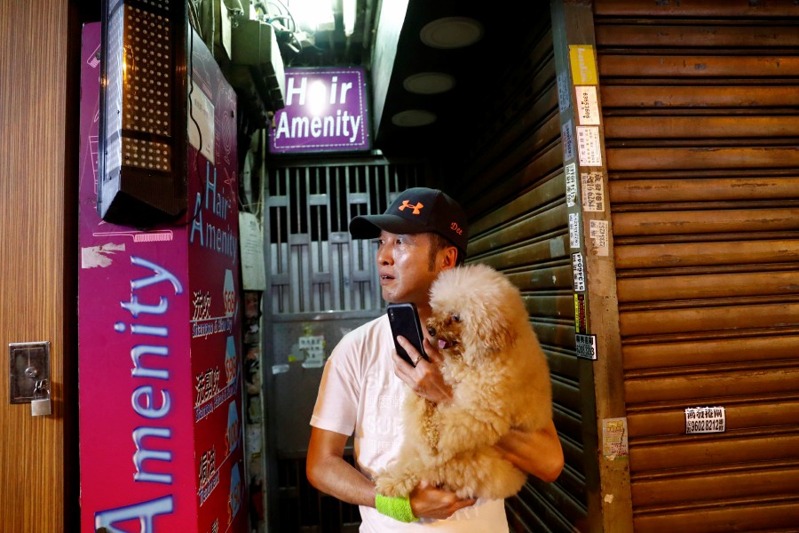 A man carries his dog during a protest near Prince Edward MTR station in Hong Kong. - Reuters