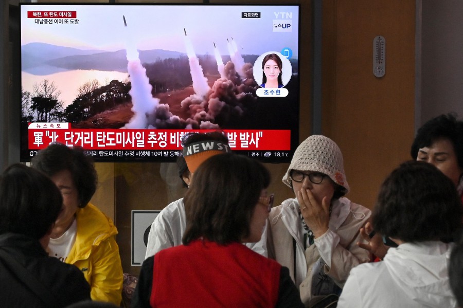 People sit in front of a television screen, showing a news broadcast with file footage of a North Korean missile test, at a train station in Seoul. - AFP PIC