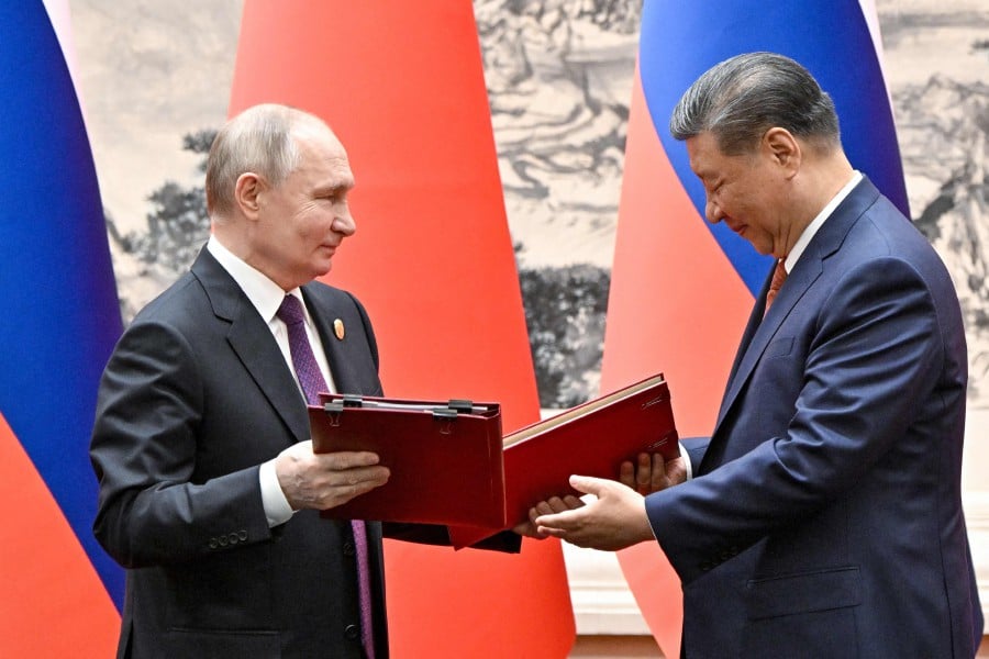 Russia's President Vladimir Putin and China's President Xi Jinping exchange documents during a signing ceremony following their talks in Beijing. - AFP PIC