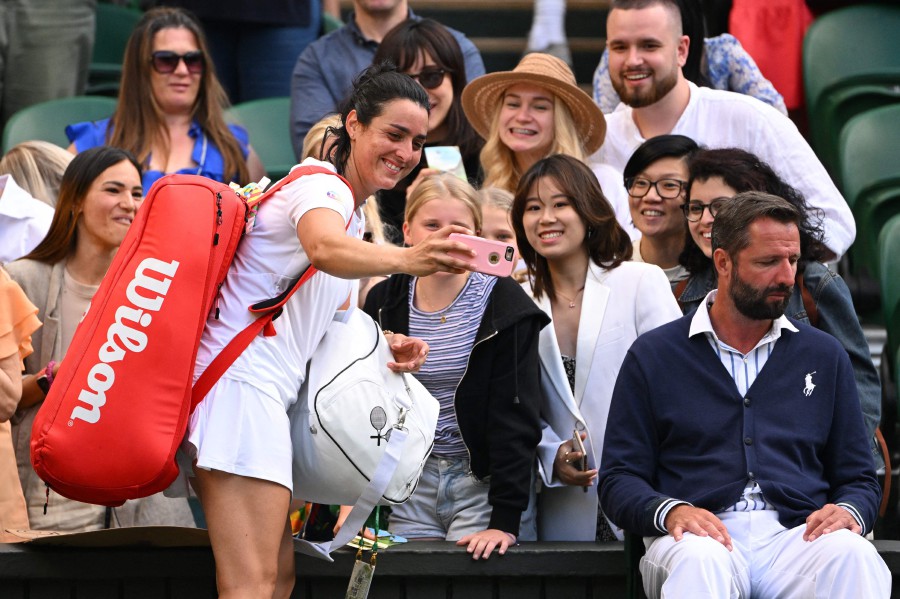 Tunisia's Ons Jabeur takes a selfie picture with some fans as she leaves the court after beating Czech Republic's Marie Bouzkova during their women's singles quarter final tennis match on the ninth day of the 2022 Wimbledon Championships at The All England Tennis Club in Wimbledon. - AFP PIC