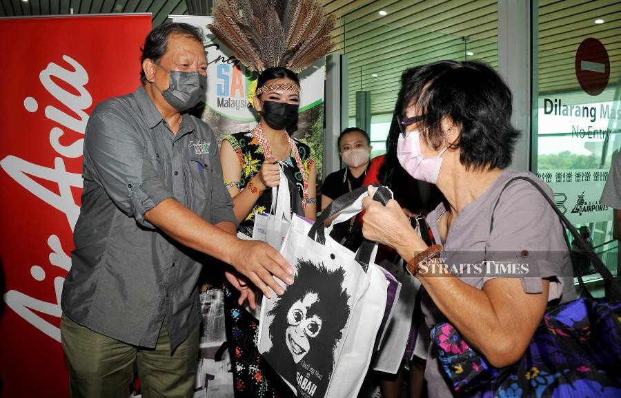 Sabah Assistant Tourism, Culture and Environment Minister Datuk Joniston Bangkuai welcoming passengers at the Kota Kinabalu International Airport. - NSTP/MOHD ADAM ARININ