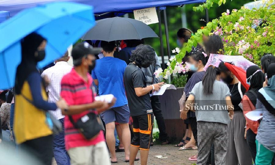 This August 26, 2021 file pic, shows people lining up for Covid-19 screening at Dewan Boling Padang, Likas. - NSTP/MOHD ADAM ARININ 