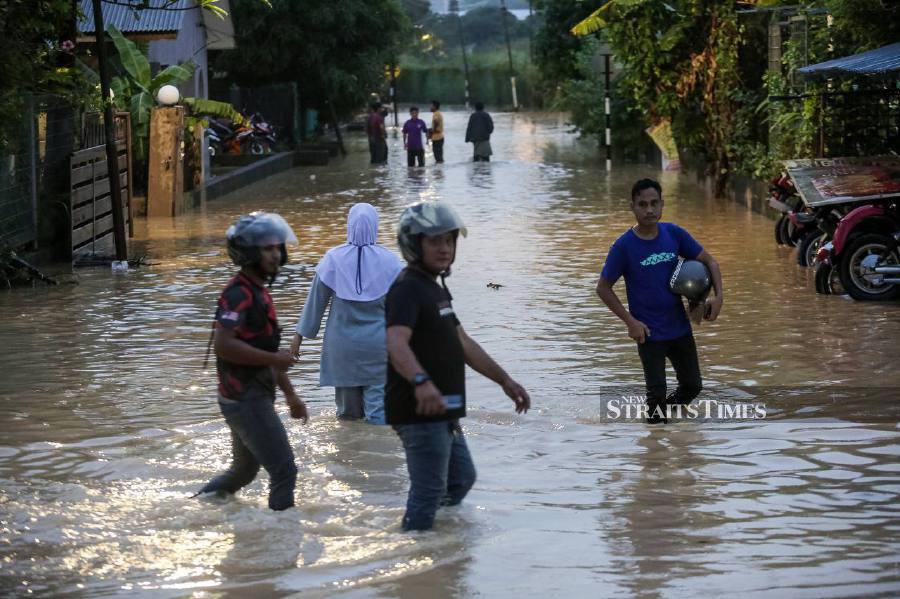 Local wade through the floodwaters following heavy rain in Kampung Melayu Subang in Subang Jaya. -NSTP/HAZREEN MOHAMAD