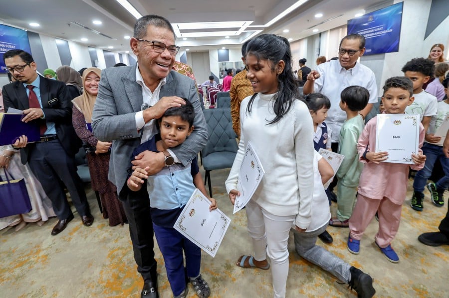 Home MinisterDatuk Seri Saifuddin Nasution Ismail having a light moment with children after presenting them with citizenship certificates at the ministry. Bernama pic