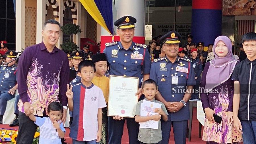 Fire and Rescue Department director, Datuk Nor Hisham Mohammad (centre) with Altamis Faiz and his family during the ceremony at the 2024 Fire and Rescue Department Annual Parade in Putrajaya. -NSTP/ Samadi Ahmad.