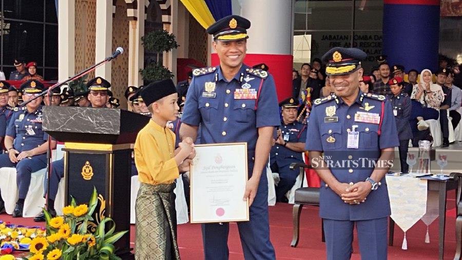 Fire and Rescue Department director, Datuk Nor Hisham Mohammad (centre) presenting a certificate to Altamis Faiz during the ceremony at the 2024 Fire and Rescue Department Annual Parade in Putrajaya. -NSTP/ Samadi Ahmad.
