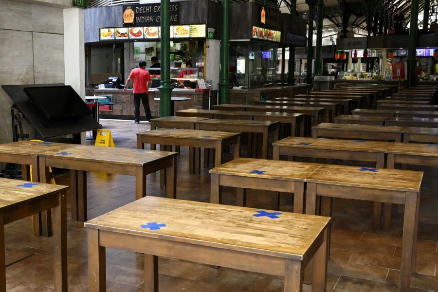 Table settings with the chair removed are seen at Lau Pa Sat food centre in the central business district of Singapore. - AFP pic