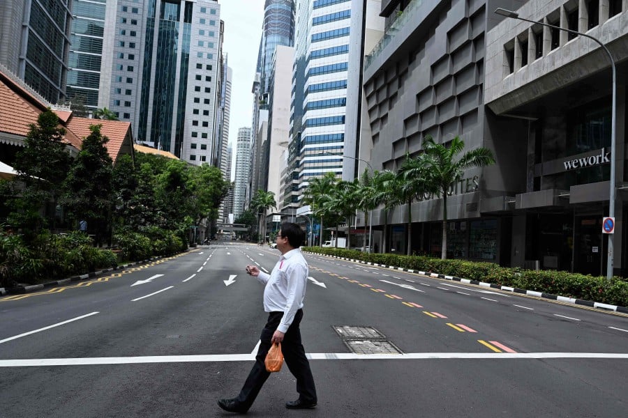 A man crosses an empty street in the central business district of Singapore. - AFP pic