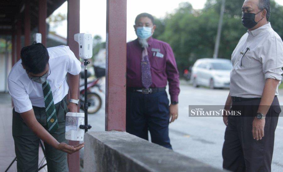  A Sijil Pelajaran Malaysia candidate sanitising his hands before entering  his school  for the oral and science laboratory examinations yesterday in Kuala Lumpur.  PIC BY MOHAMAD SHAHRIL BADRI SAALI     