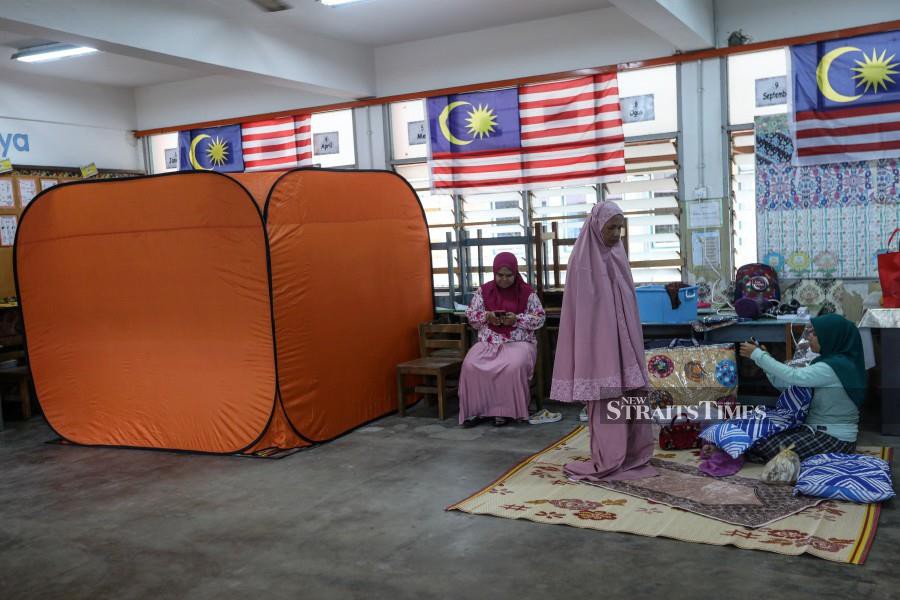  Ruhani Mohamad (centre) praying at the SK Tok Jembal relief centre following the floods in Kuala Nerus. - NSTP/GHAZALI KORI