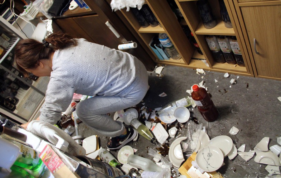  A woman cleans broken plates at a restaurant after a strong earthquake hit northeastern Japan, in Fukushima. - EPA pic