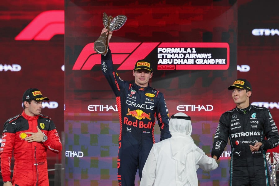 Ferrari's Monegasque driver Charles Leclerc (L) and Mercedes' British driver George Russell (R) watch as Red Bull Racing's Dutch driver Max Verstappen celebrates with the winners trophy on the podium after the Abu Dhabi Formula One Grand Prix at the Yas Marina Circuit in the Emirati city on November 26, 2023. -- Pic: AFP