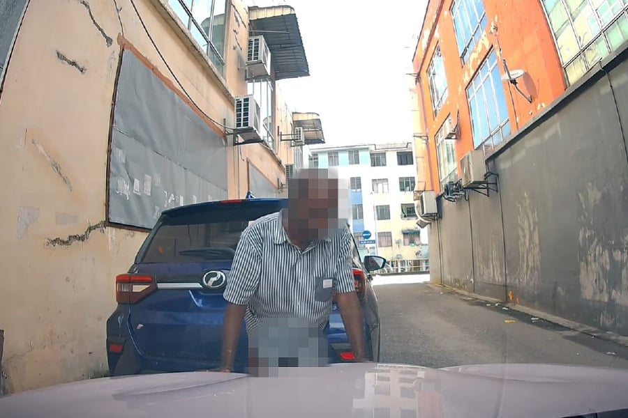 The incident, which was captured by the dashboard camera of a vehicle at the location showed the man casually lowered his trousers before defecating behind a blue Perodua Ativa. - Pic screengrab from DashCam Owners Malaysia Facebook