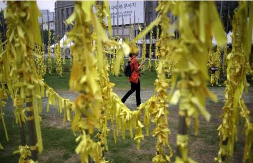 A woman walks near yellow ribbons with messages for missing passengers and victims aboard the sunken ferry Sewol in the water off the southern coast, at a group memorial altar in Seoul, South Korea. South Korean students who survived April's deadly ferry disaster say they were repeatedly ordered by loudspeaker to stay in the sinking ship but eventually helped each other flee after their cabins were flooded too much. AP Photo