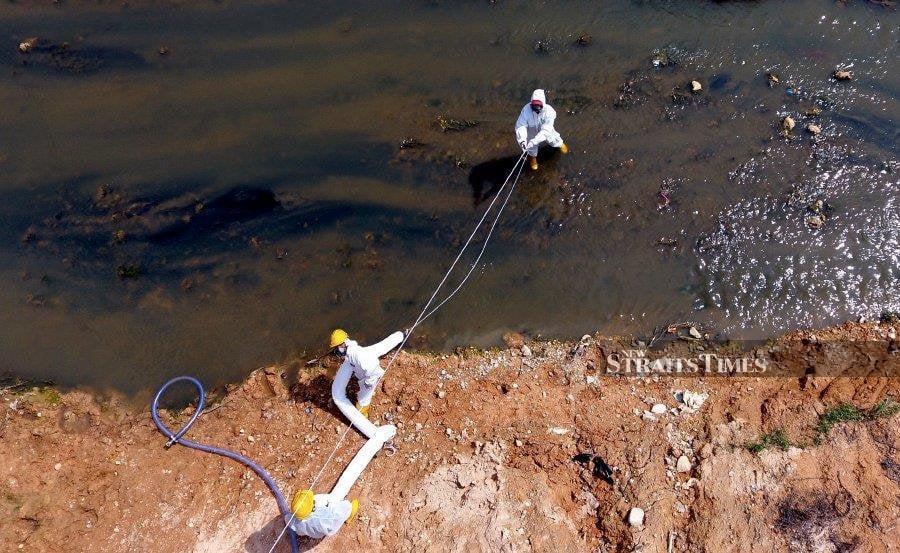 Workers with a cleaning company collecting chemical waste from Sungai Kim Kim on March 14, 2019. - NSTP file pic