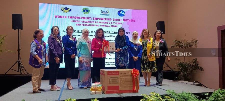 Immediate Past District Governor District 308-A2 Kapitan Connie Loh Ming Hua presenting the oven to one of 20 single women during the Empowering Women for Single Mothers' in conjunction with International Women's Day yesterday at Sabah International Convention Centre (SICC) here. Present were Sabah Single Mothers Association (PITSA) president Norhanida Annol (third right) and SICC CEO Datuk Rosmawati Lasuki(fourth left).- Pic credit: NSTP/OLIVIA MIWIL