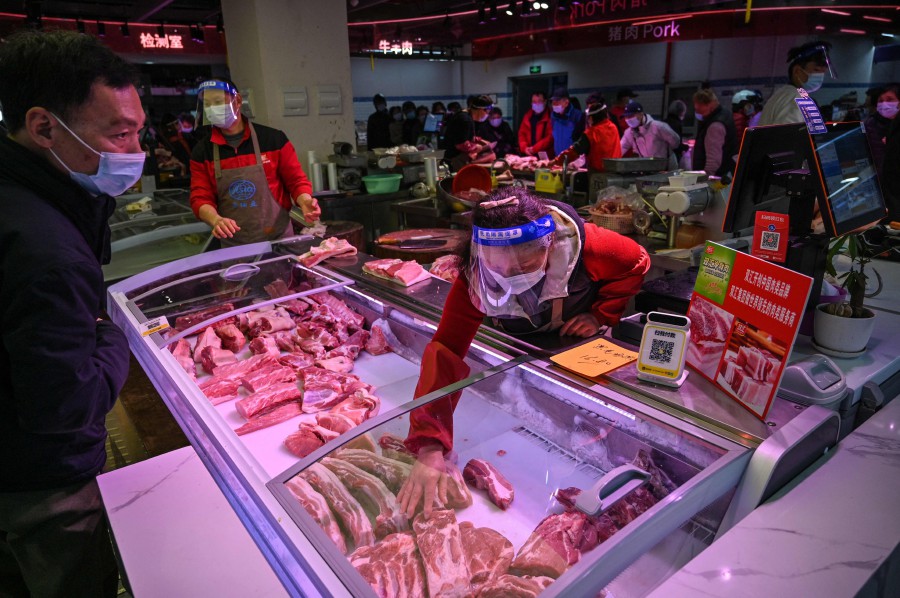 Sellers and customers are seen inside of a market in Jing'an district, in Shanghai. - AFP PIC 
