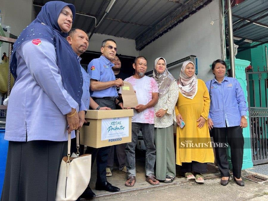 Social Security Organisation (Socso) chief executive officer Datuk Seri Dr Mohammed Azman Aziz Mohammed presenting funeral benefit allowance to Mohd Salleh Othman, 57, father of delivery rider Muhammad Hafiz Mohd Salleh, 32, who was killed in the plane crash tragedy near Elmina, Shah Alam, on Aug 17. - NSTP/Adie Zulkifli