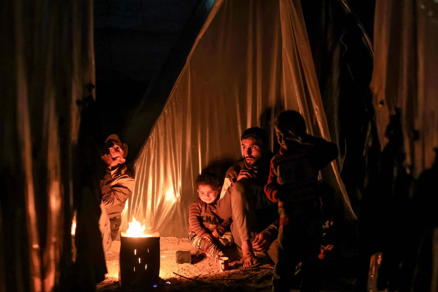  A man sits with children by a fire outside one of the tents housing Palestinians displaced by the conflict in Gaza between Israel and Hamas in Rafah in the southern Gaza Strip. - AFP PIC