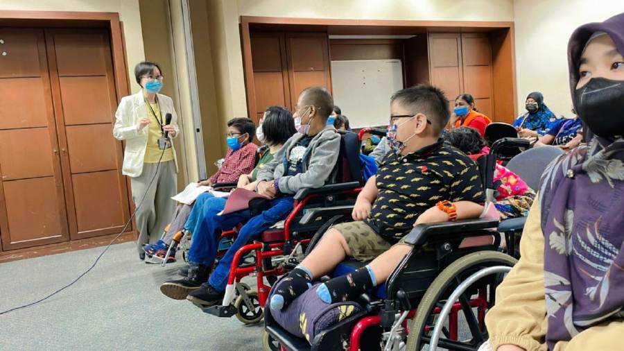 Young spina bifida patients (in wheelchairs) listen attentively as Dr. Sharon Anne Khor (standing) addresses them. - Pic courtesy of HSI