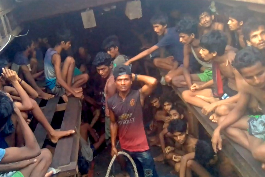 This video grab taken on December 4, 2020 from an AFPTV video shows a Burmese smuggler (C) along with Rohingya refugees in a boat in Chakmarkul on August 26, 2020. -AFP pic/Handout