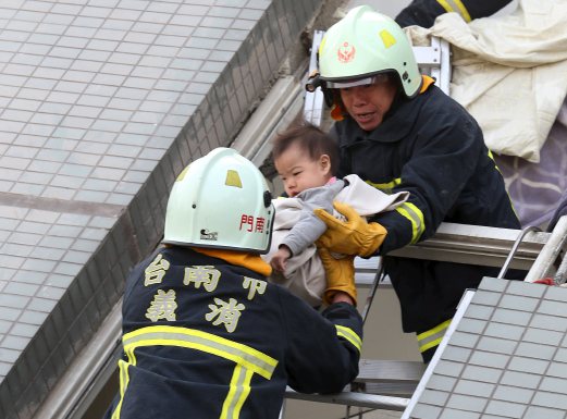 Rescue workers remove a baby from the site where a 17-storey apartment building collapsed after an earthquake hit Tainan. REUTERS
