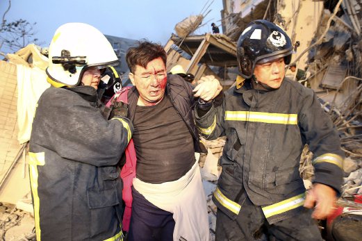 Rescue personnel help a victim at a damaged building. REUTERS