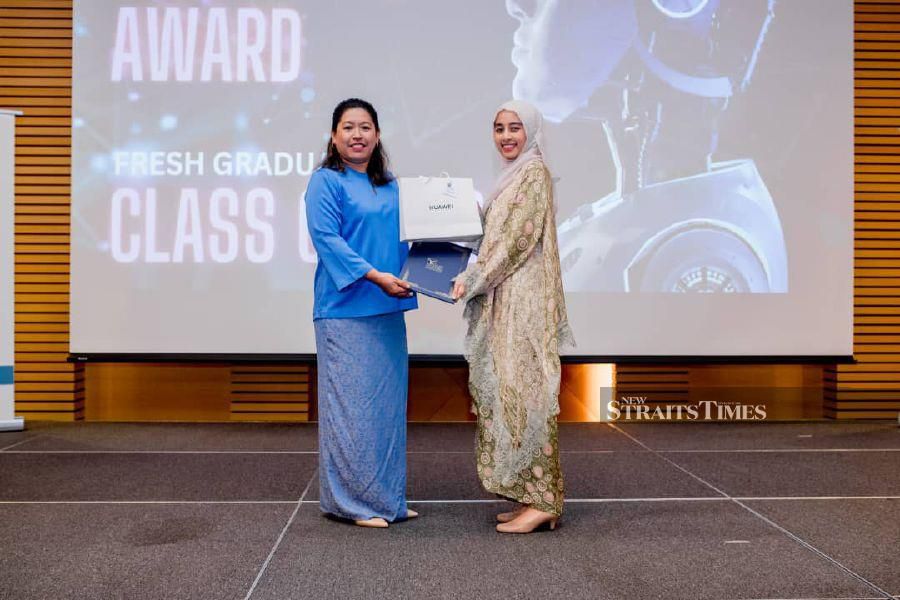 One of the recipients of the Excellence Performance Award class of 2020, Izzah Athirah Mohamad Radzi (right) receives her certificate from Noralyn Idris