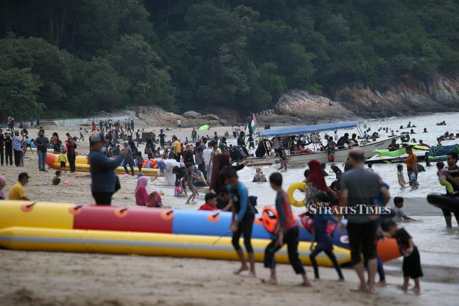 Visitors enjoying various water activities at Teluk Batik Beach in Lumut, Perak. - NSTP/SHARUL HAFIZ ZAM