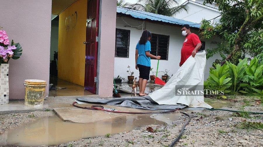 Resident in Kampung Sulup, Teluk Kumbar, seen cleaning following the flood situation. - NSTP/MIKAIL ONG