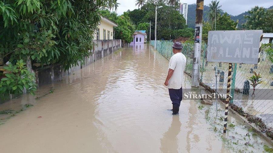 A resident in Kampung Sulup, Teluk Kumbar, checks on the flood situation. - NSTP/MIKAIL ONG