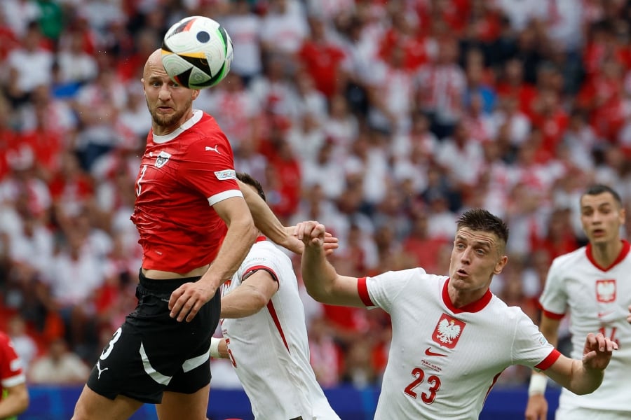 Austria’s Gernot Trauner (left) heads the ball as he is marked by Poland’s Krzysztof Piatek during Friday’s Euro 2024 Group D match at the Olympiastadion in Berlin. - AFP PIC