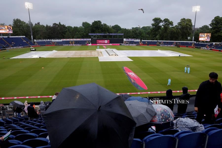 Spectators sit with umbrellas in the stand as rain delays the start of play for the Third T20 International between England and Pakistan at the Sophia Gardens Cricket Ground in Cardiff, Wales on Tuesday. - REUTERS PIC