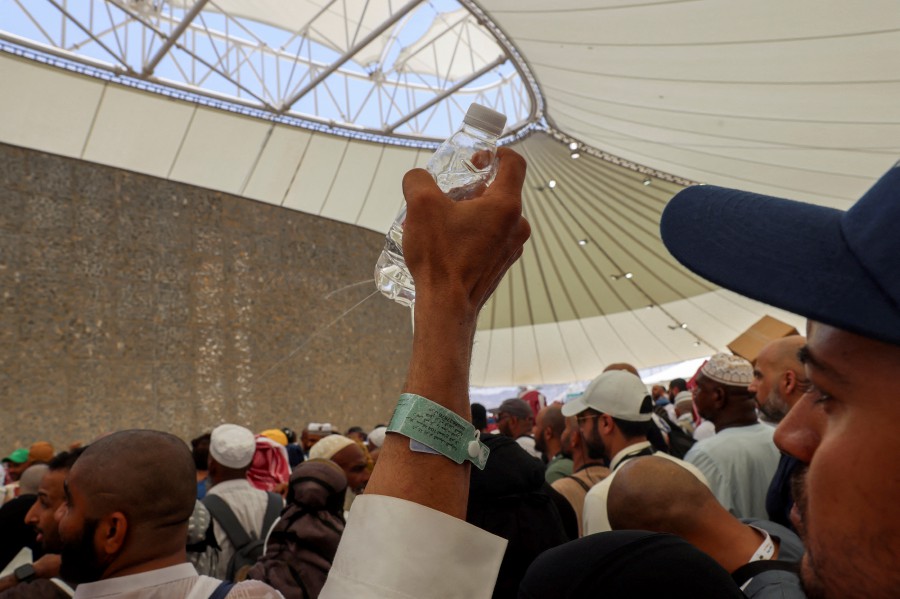 A Muslim pilgrim sprinkles water onto pilgrims to cool them down as they take part in the stoning ritual, amid extremely hot weather, during the annual haj pilgrimage, in Mina, Saudi Arabia, June 18, 2024. REUTERS