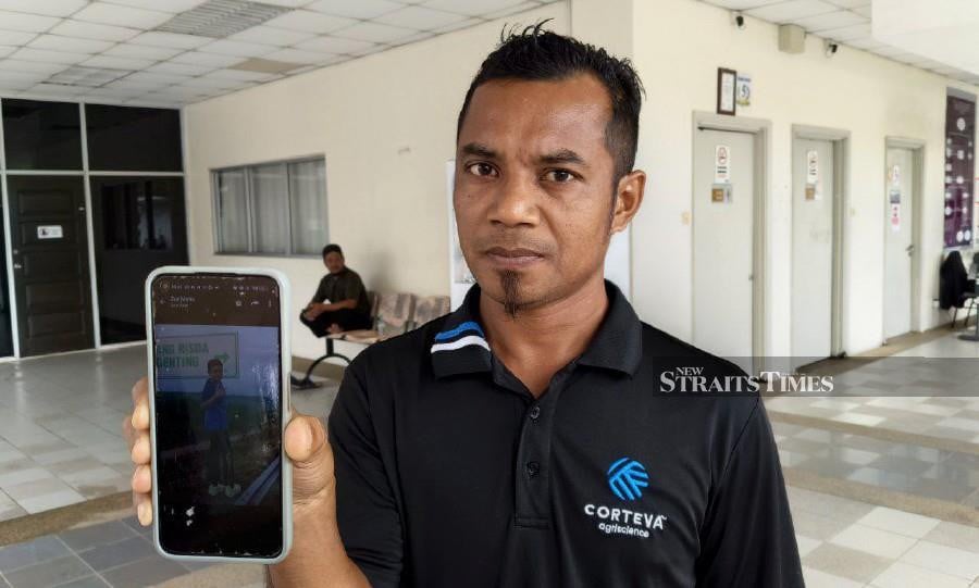 Mohd Hashim Nazri, 36, showing a photograph of his son, Muhammad Aiman Harith Mohd Hashim, 10, was found drowned in a drainage sump at Perumahan Universiti Utara Malaysia (UUM) in Sintok yesterday. -- NSTP/ZULIATY ZULKIFFLI