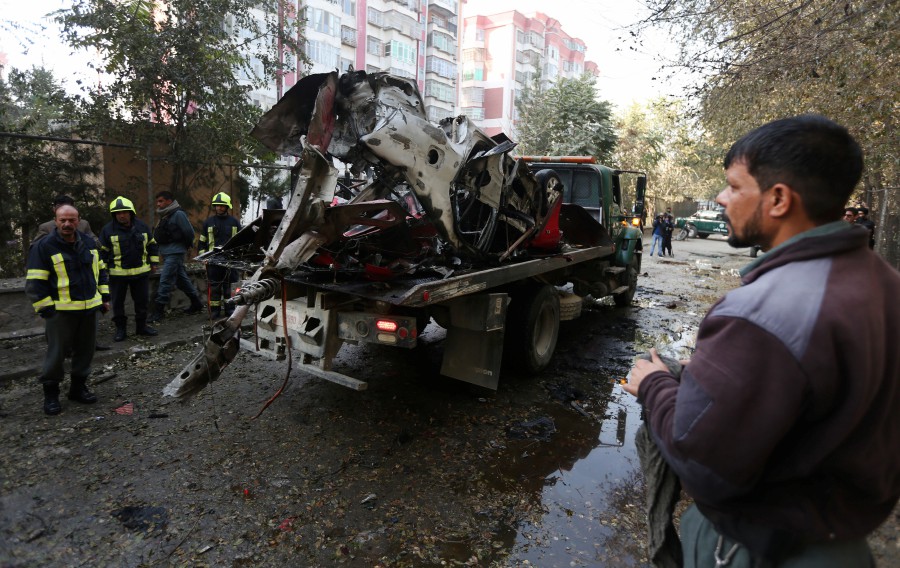 Kabul police officers remove the wreckage of a damaged car from the scene of an explosion in Kabul, Afghanistan. According to local reports, three people, including former Afghan local TV journalist Yama Siawash, were killed in the blast. -- EPA