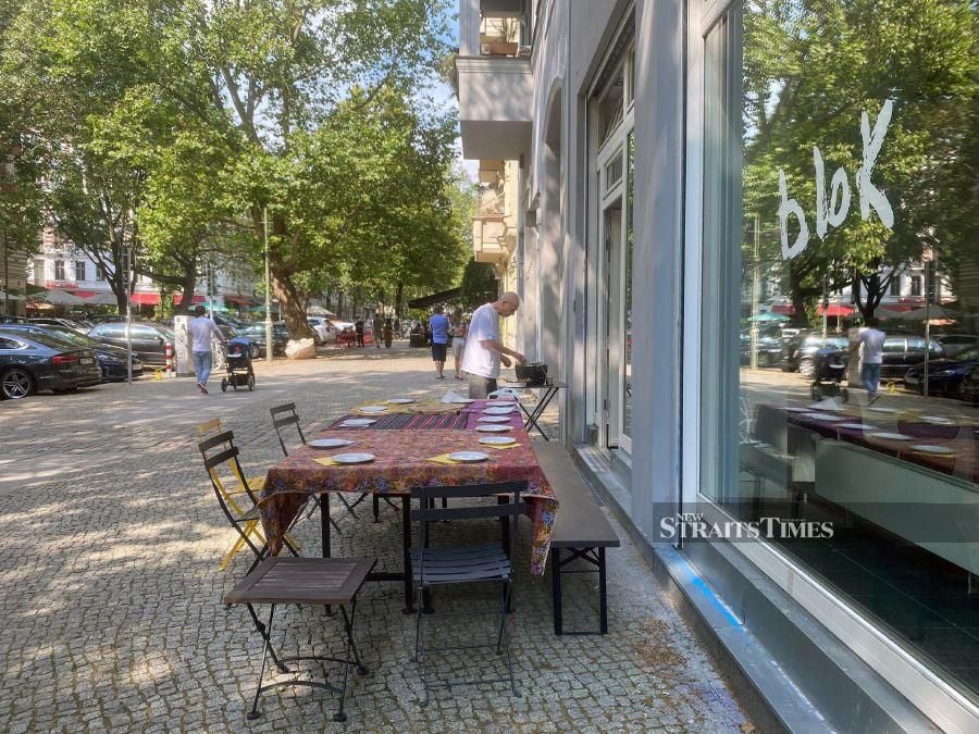  Preparing for the Malaysian High Tea event staged on the broad pavement in front of their building in the Kollwitzstrasse in Berlin Prenzlauer Berg.