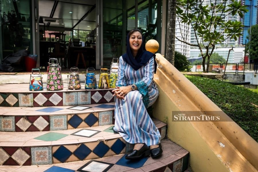  Nor Fadilah Mohd Nizar with some of her hand-painted tiffins. Photo by Kenny Loh.