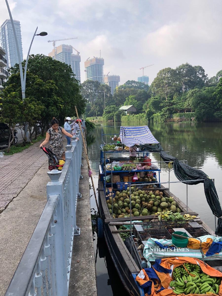  A contrasting sight between rising new condos and poor boat people selling their farm produce by the river.