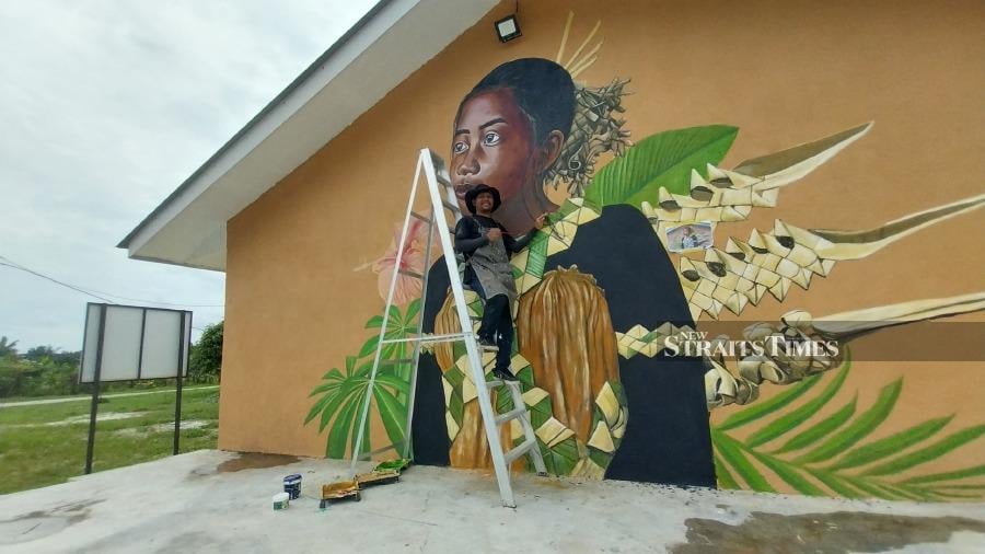  Painting the mural on the wall of the Temuan Cultural Infomation Centre at his village.