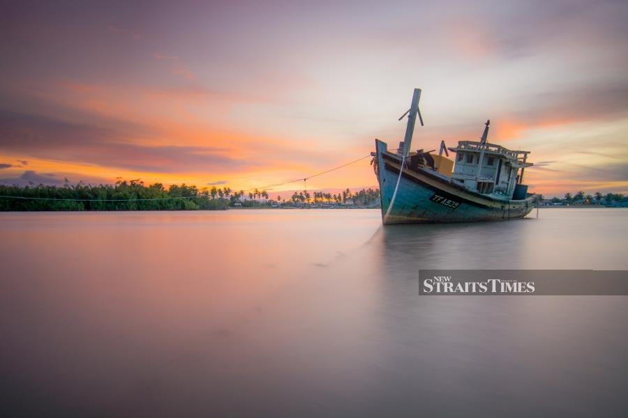  A stranded fishing boat during sunset.