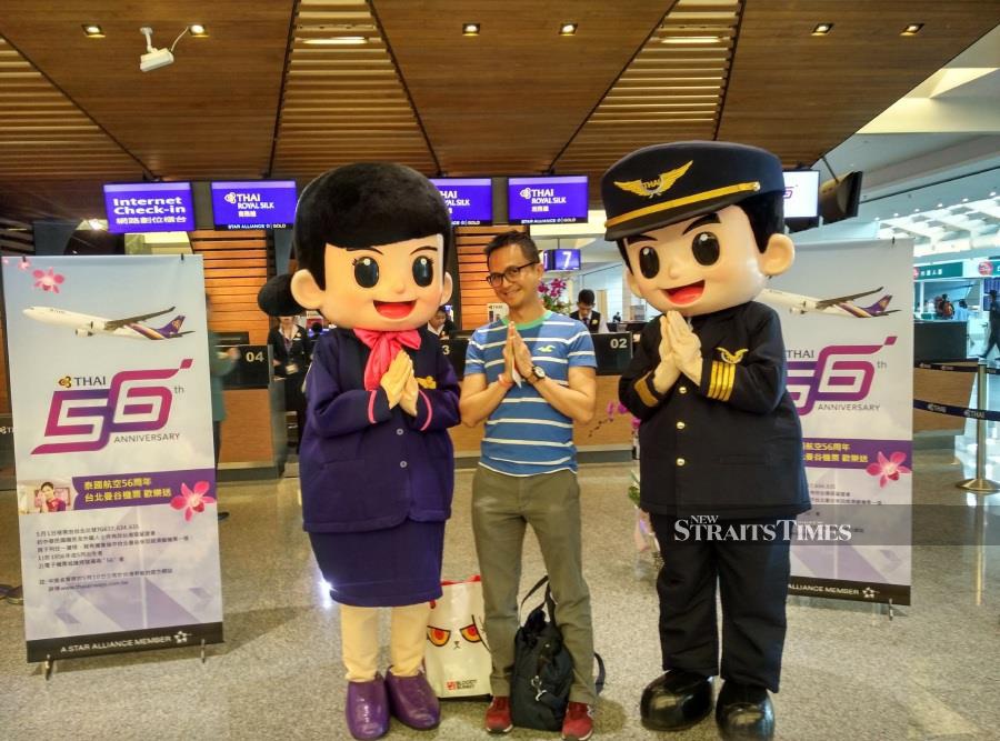  See in a lighthearted pose with Thai Airways mascots in Bangkok, Thailand.