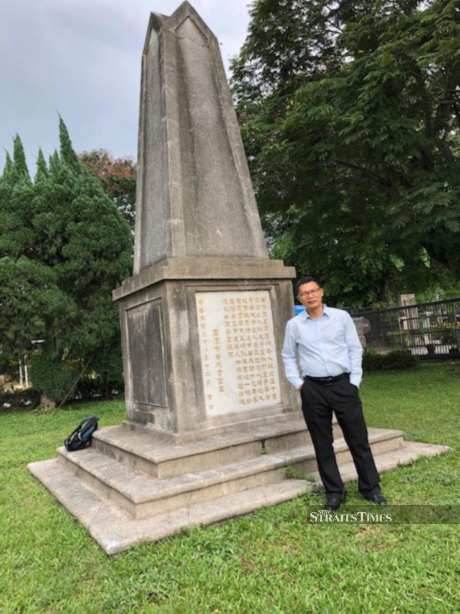  Principal Lim standing by the war memorial.