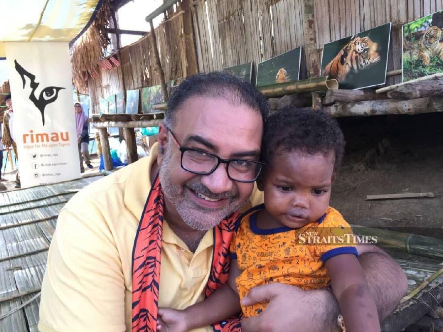 Datuk Vinod Sekhar with a young orang asli child during his recent visit to the Royal Belum Forest in Perak.