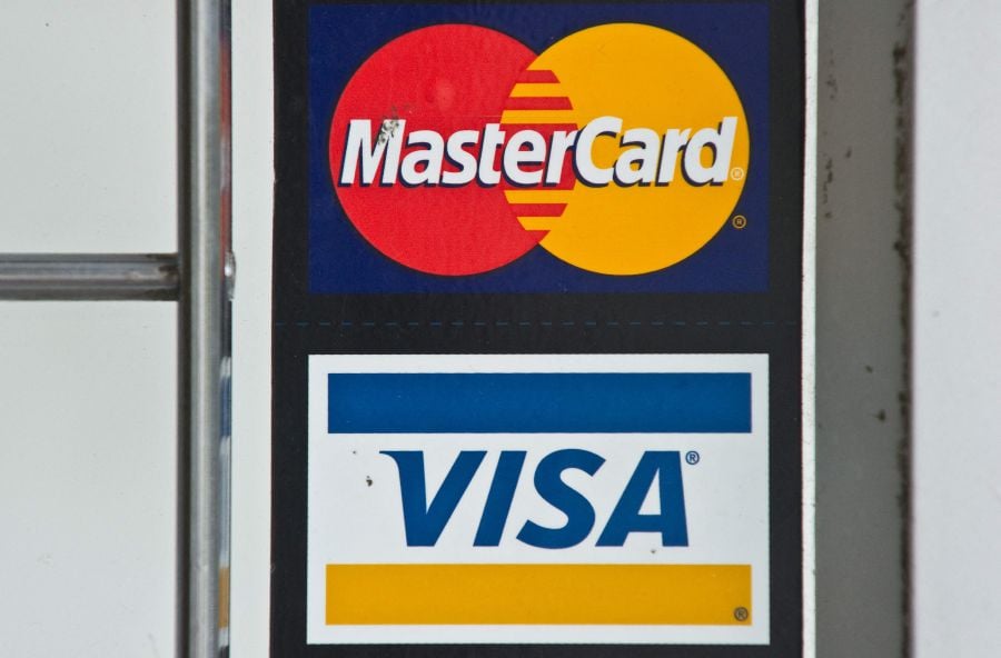 (FILES) In this file photo taken on March 30, 2012, Visa and MasterCard credit card logos are seen in a store window in Washington, DC. - Card payment giants Visa and Mastercard announced on March 5, 2022, they will suspend operations in Russia, the latest major US firms to join the business freeze-out of Moscow over its invasion of Ukraine. (Photo by NICHOLAS KAMM / AFP)