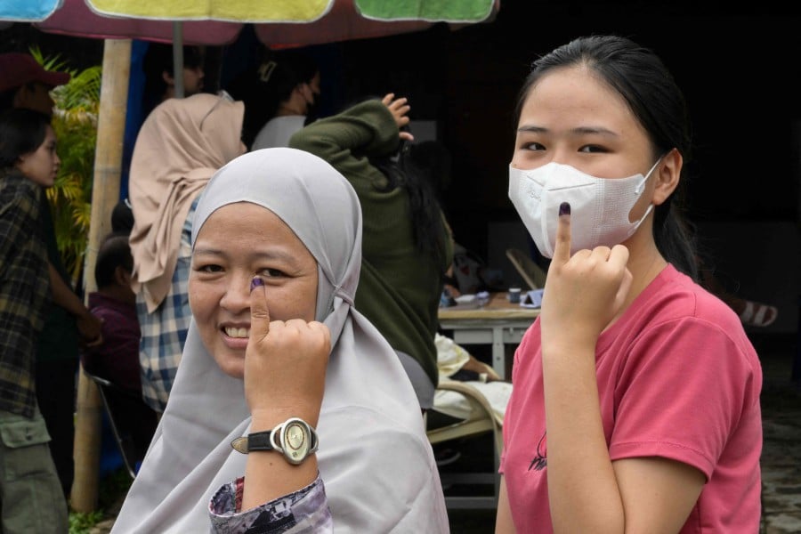 Two women show their ink-stained fingers after voting in Indonesia's presidential and legislative elections in Jakarta. - AFP PIC